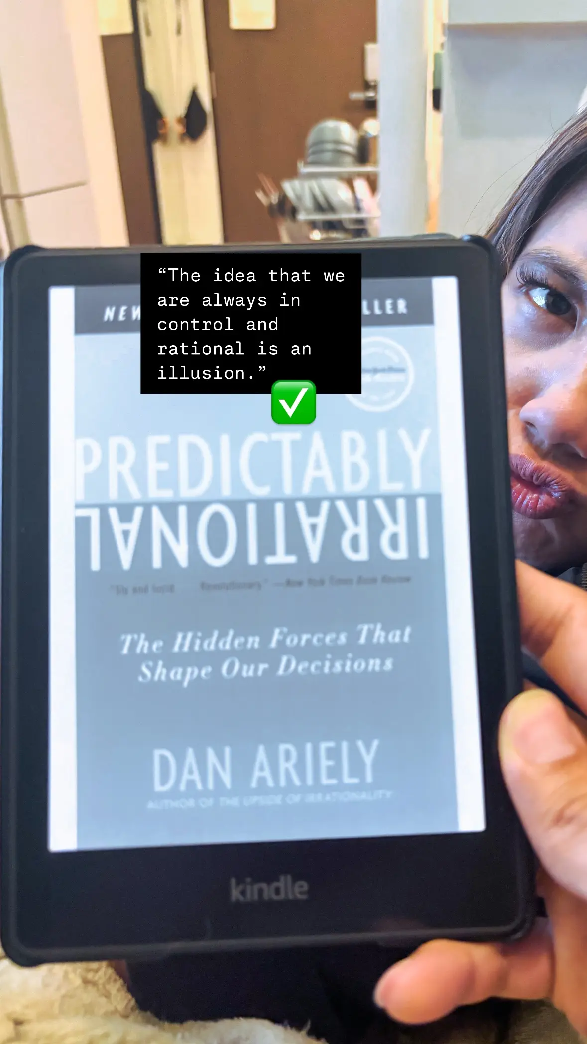 Photo of me holding a Kindle displaying the cover page of "Predictably Irrational"
